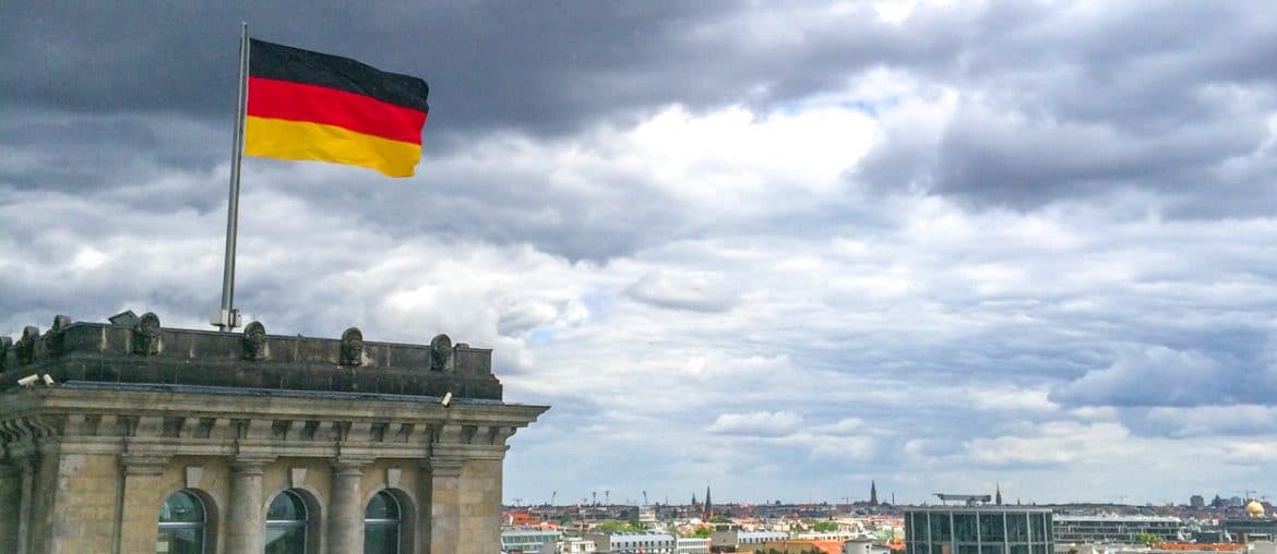 german flag flying with city behind traveling to germany for the first time