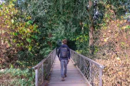 man with backpack walking along bridge in forest gifts for someone going travelling