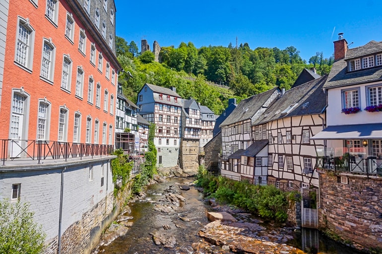 Bunte Fachwerkhäuser und Fluss mit Bäumen im Hintergrund Monschau schöne Städte