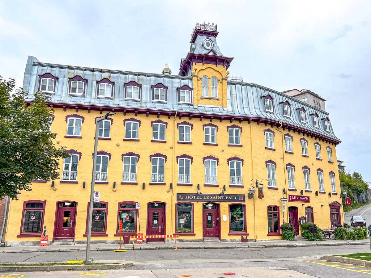 Ein großes gelbes Hotel mit Fenstern und einem Turm in der Mitte, vor dem die Straße verläuft.