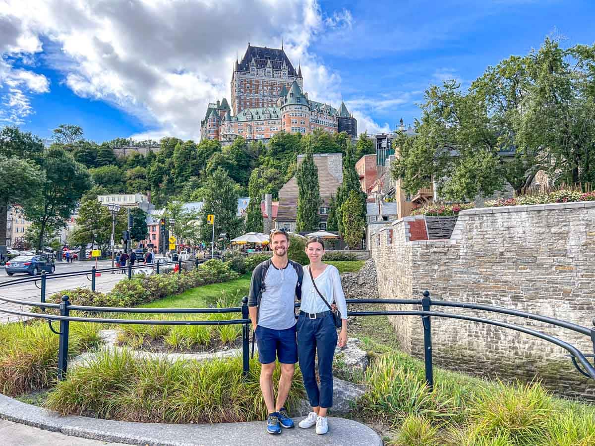 Mann und Frau posieren mit dem berühmten Hotel auf der Klippe und Gärten im Hintergrund.