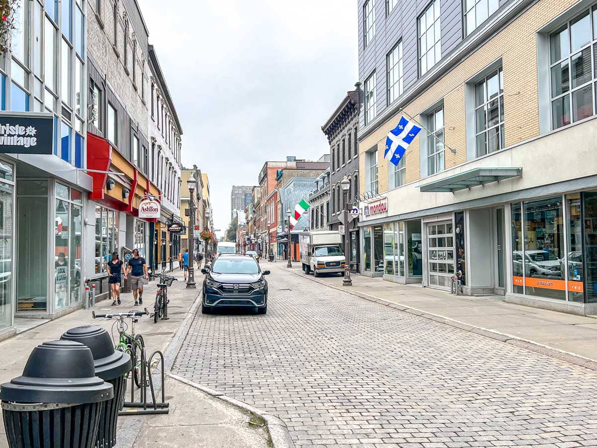 Belebte Stadtstraße mit parkenden Autos und Ladenfronten entlang des Bürgersteigs in Saint-Roch.